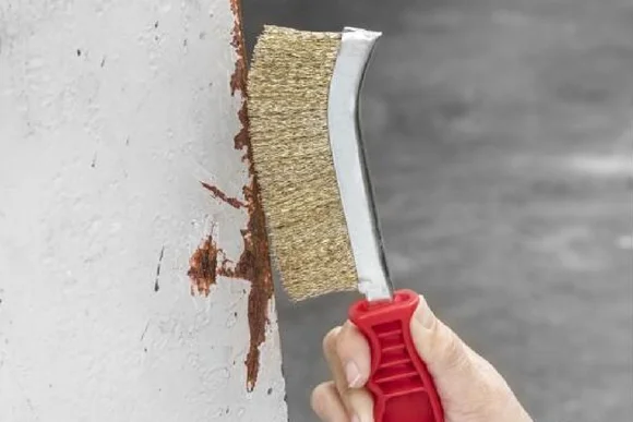 Hand entfernt Rost mit Drahtbürste